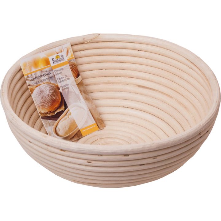 Rundes Gärkörbchen aus hellem, spiralförmig gewickeltem Naturmaterial (vermutlich Rattan), mit einer glatten Innenstruktur zur Teigführung beim Brotbacken. Im Körbchen liegt ein Produktetikett mit dem Aufdruck „Gärkörbchen“ sowie einer Abbildung eines Bro